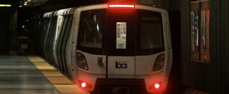 BART train arriving at a dimly lit underground station in San Francisco.