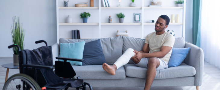 Young man sitting on couch with a cast on his right leg