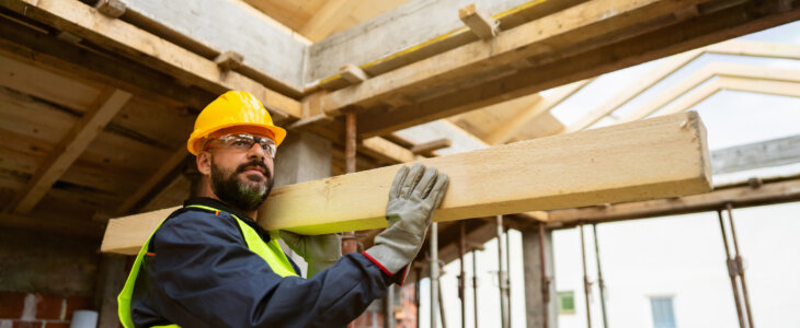 construction worker carrying a timber on his shoulder