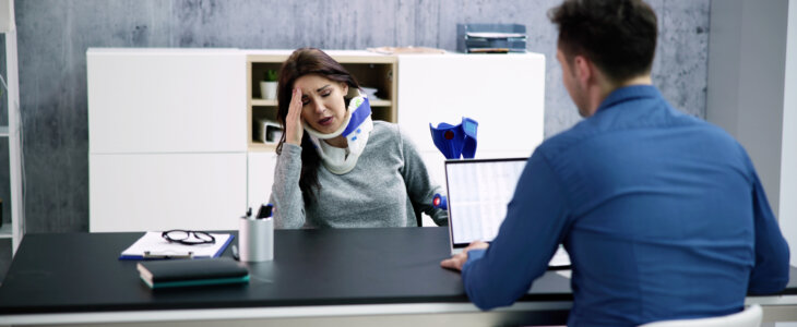 Injured woman with neck brace and injury lawyer meeting