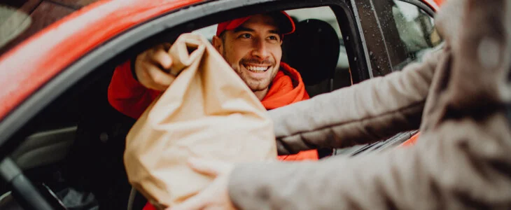 smiling food delivery driver handing customer their order