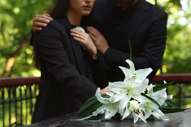 People wearing black grieving at gravesite